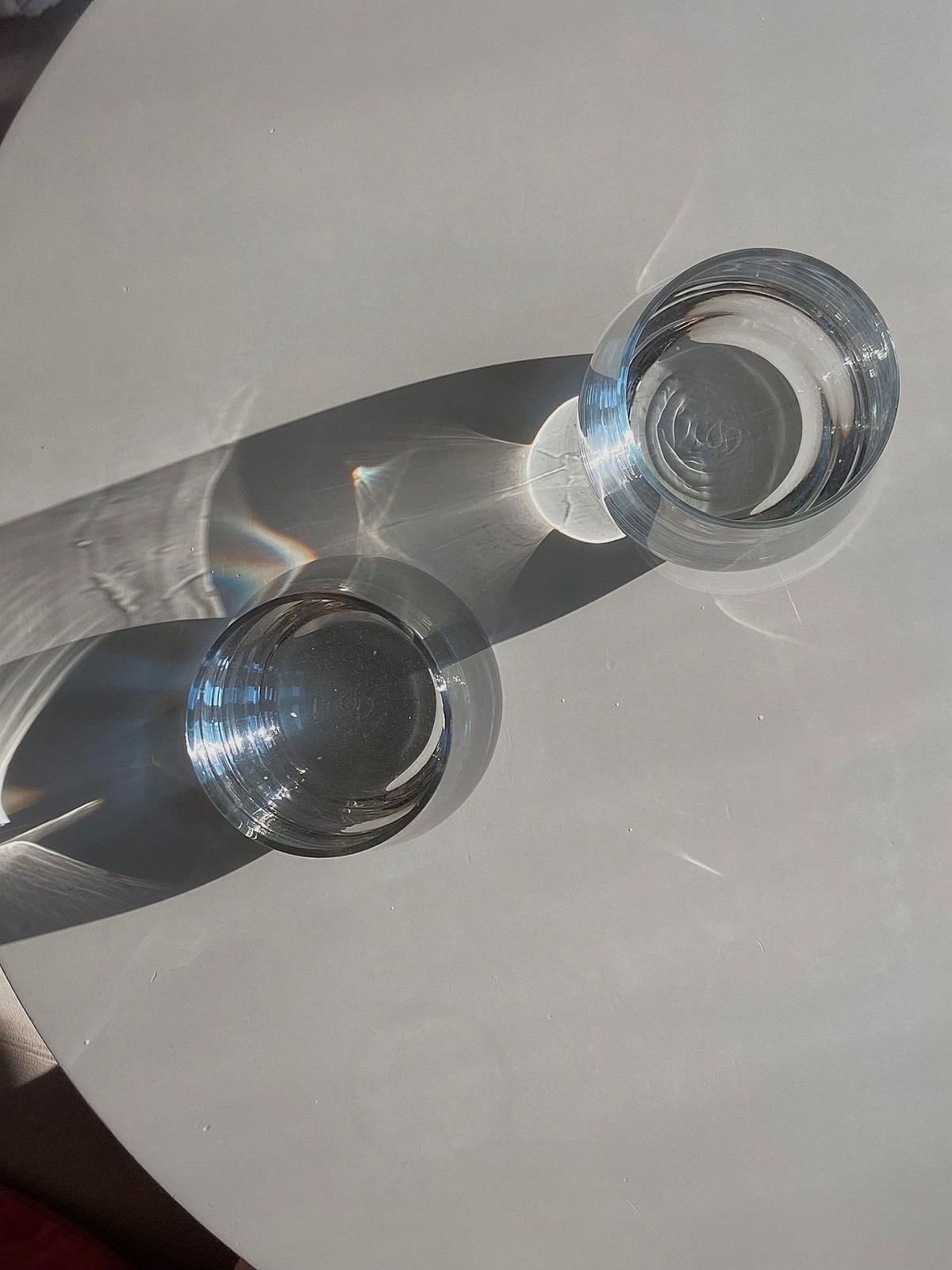 Two clear glasses seen from above, light bending through them.