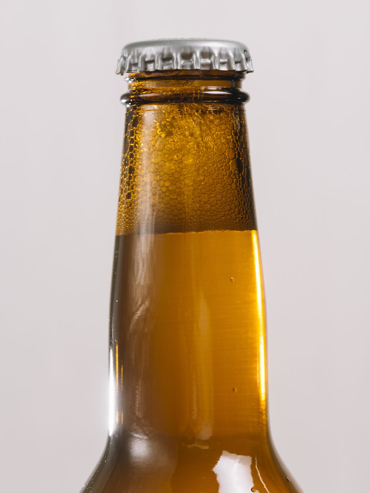Close-up of the neck of an amber glass bottle.