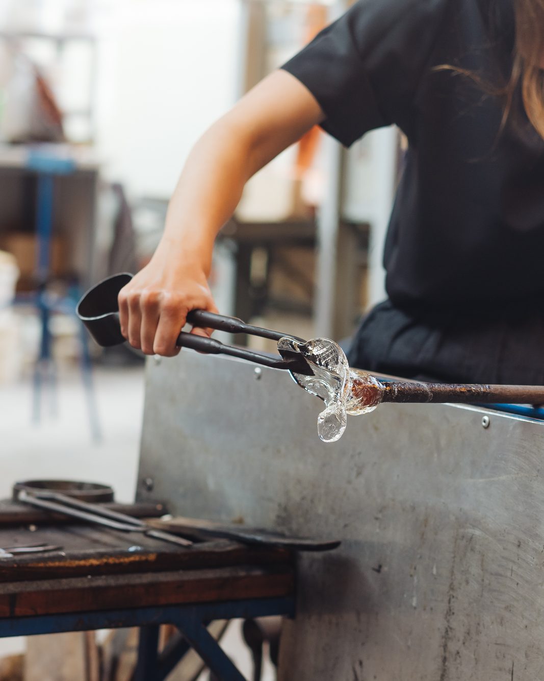 A trainee shaping a small glass flower at the bench.
