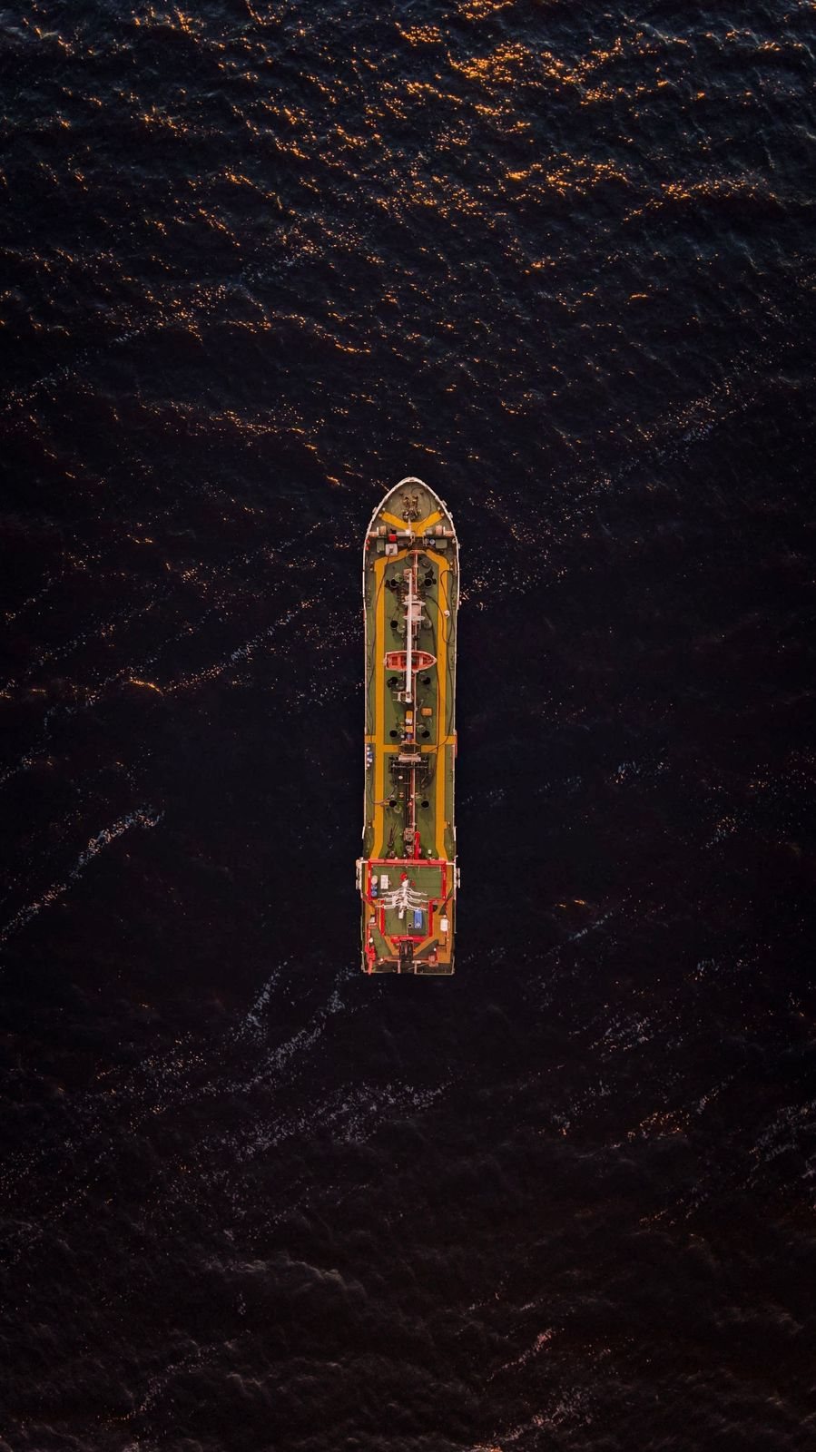 A cargo ship on dark open water, seen from above.